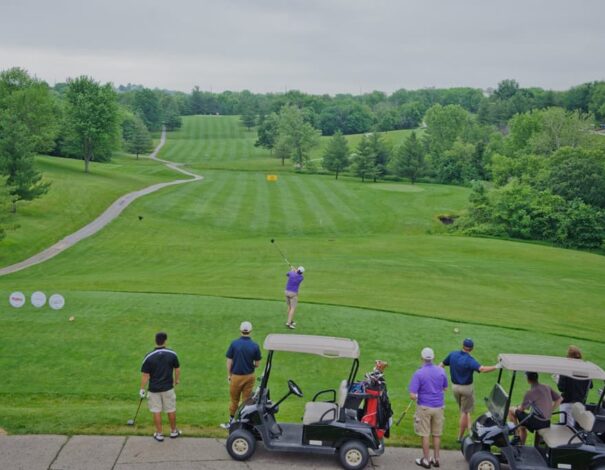 Golf carts with golfers watching person hit the ball Golf carts with golfers watching person hit the ball